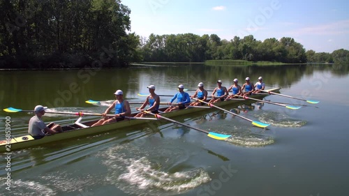 Rowing team summer training. 8 athletes rowers in a boat in the river Dnipro. City area in Kiev, Ukraine