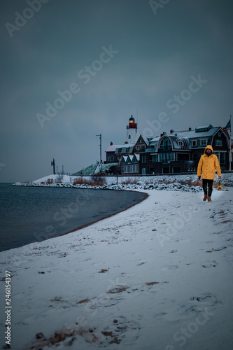 Men with yellow rain coat and oil lamp at the beach of Urk Netherlands during snowy winter weather, winter wonderland Lighthouse Urk Holland Netherlands photo