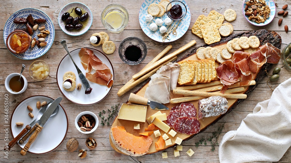 Fototapeta premium Appetizers table with various of cheese, curred meat, sausage, olives and nuts Festive family or party snack concept. Overhead view.