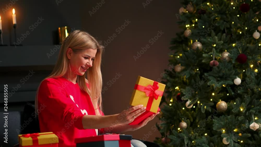 Girl with Christmas hat makes wishes and opens a Christmas gift package.concept of holidays and new year.the girl is happy and smiles with christmas gift in hand. Girl with Christmas hat makes wishes and opens a Christmas gift package.concept of holidays and new year.the girl is happy and smiles with christmas gift in hand.