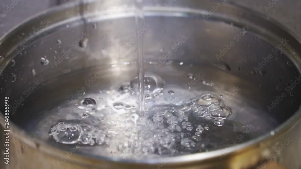 Clean water is poured into a metal pan in slow mo Clean water is poured into a metal pan in slow mo