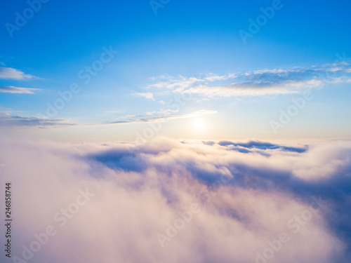 Fototapeta Naklejka Na Ścianę i Meble -  Aerial view White clouds in blue sky. Top view. View from drone. Aerial bird's eye view. Aerial top view cloudscape. Texture of clouds. View from above. Sunrise or sunset over clouds