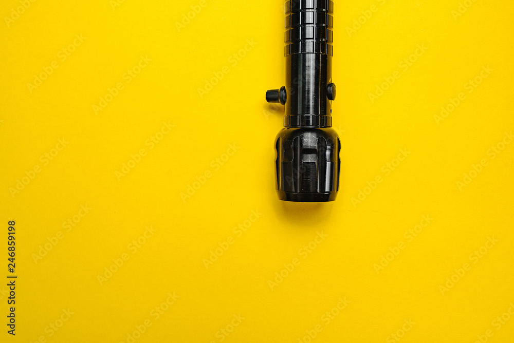 Travel and Search. Close-up of a flashlight on yellow background.