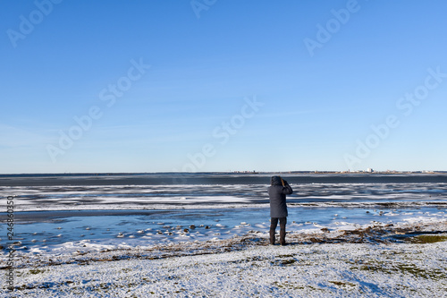 Lone birdwatcher by an icy coast