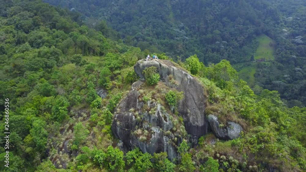AERIAL: extremely far pull away from a group of anonymous tourists standing on the great Pico de Aguila standing tall above Cali, Colombia