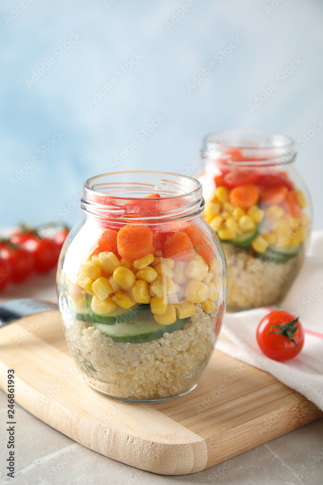 Jars with healthy quinoa salad and vegetables on table. Space for text Jars with healthy quinoa salad and vegetables on table. Space for text