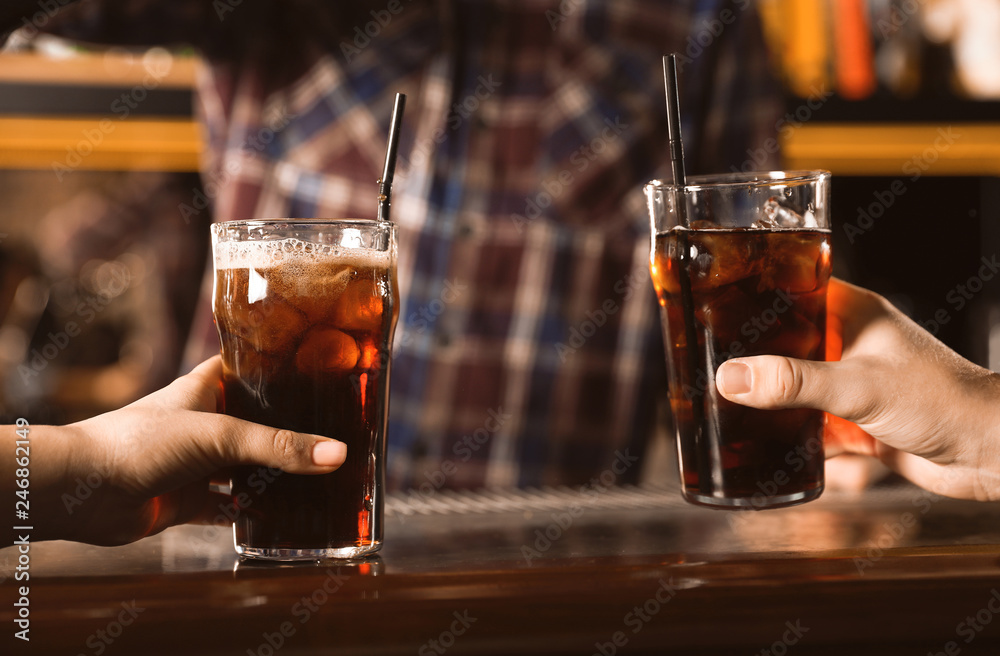Couple with glasses of refreshing cola at bar counter, closeup Couple with glasses of refreshing cola at bar counter, closeup