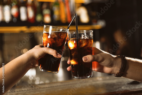 Young couple with glasses of cola in bar, closeup photo