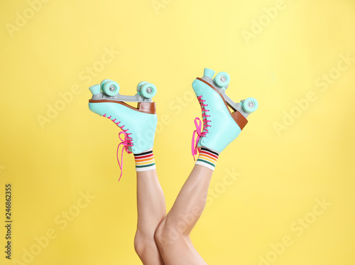 Fotografie Young woman with retro roller skates on color background, closeup