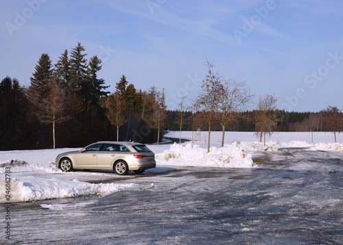 Parkendes Auto auf Parkplatz im Winter mit Schnee und Eis