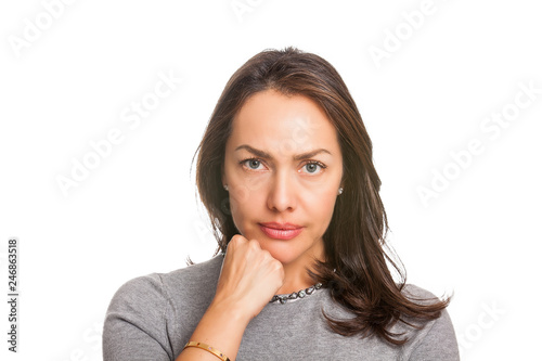 Upset unsatisfied woman standing with hand on chin and looking at camera isolated over white background