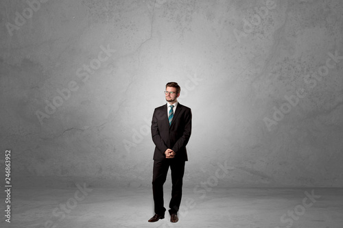 Alone handsome businessman standing in a dark empty room