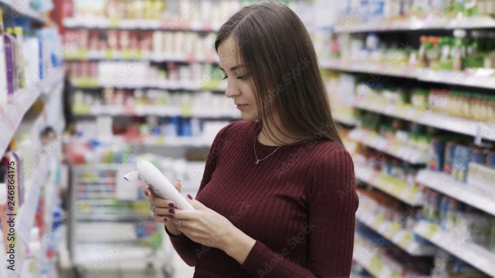 Attractive woman takes shower gel and sniffs it in supermarket, emotion like the product Attractive woman takes shower gel and sniffs it in supermarket, emotion like the product