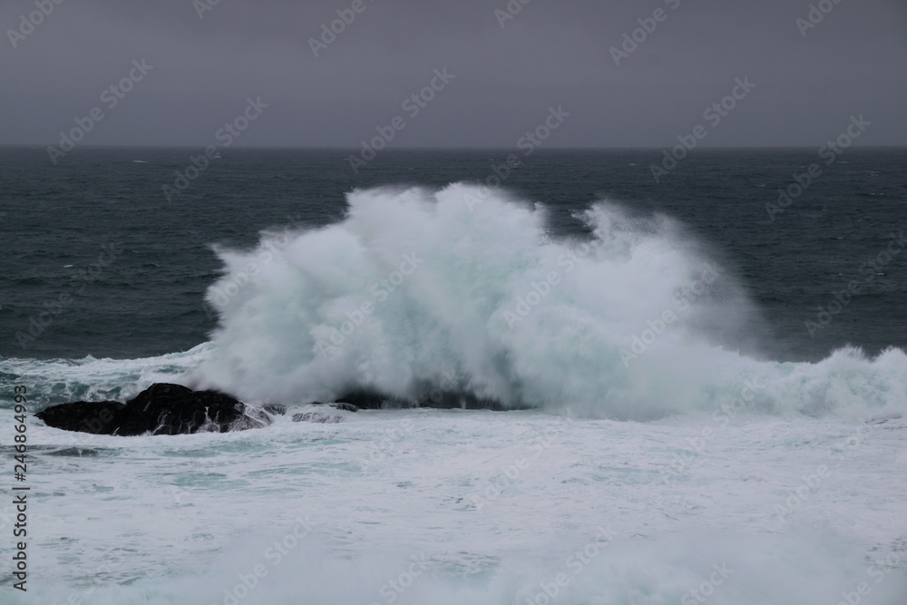 wave crashing into a rock on a rainy day
