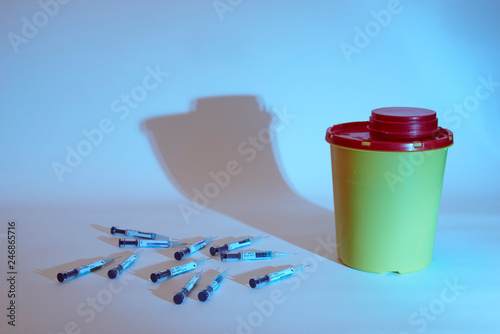 Needle and safety yellow bin over white background with dramatic shadow
