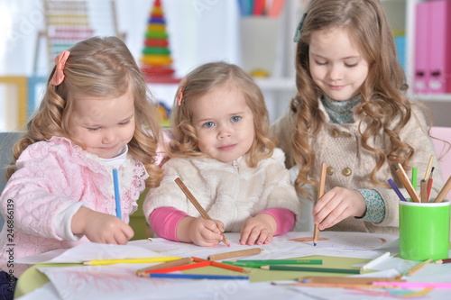 Portrait of three cute little girls drawing