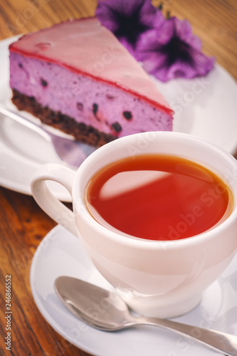Cup of fresh hot tea with delicious piece of blueberry cake on the wooden table