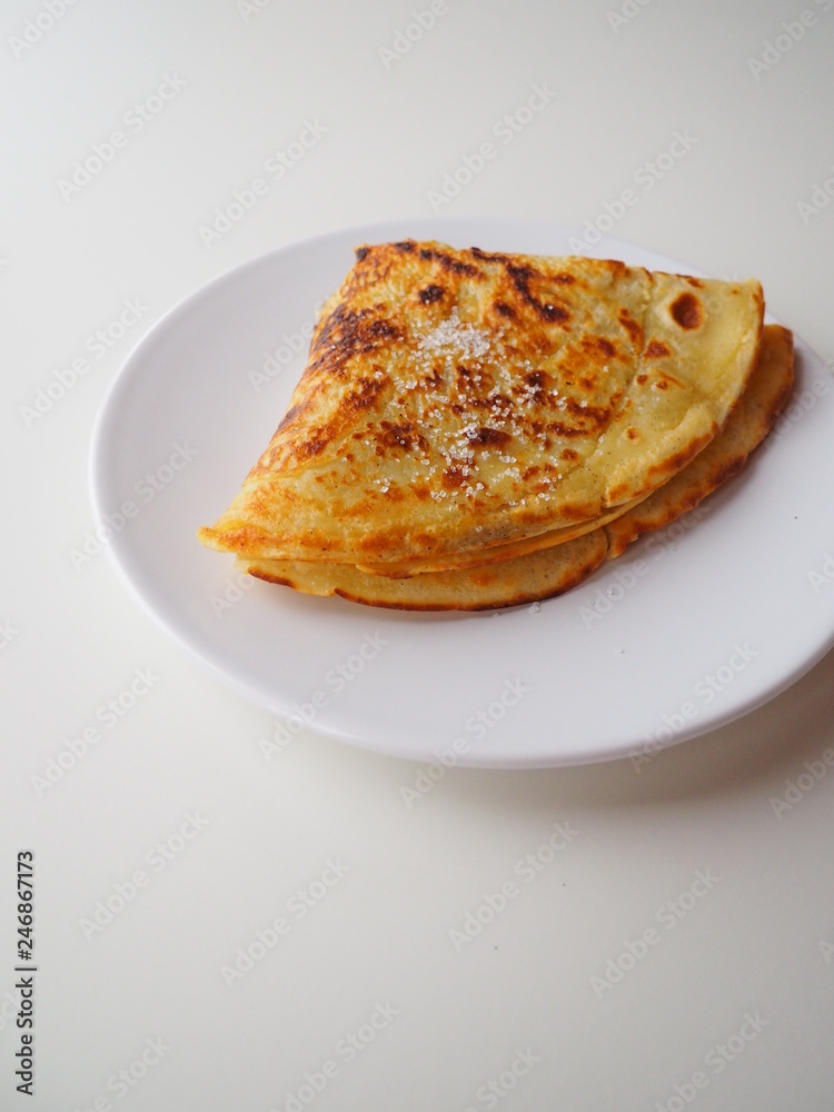 Traditional french crepe (or pancake) on a white plate, with sugar on top (called crêpe Suzette), white background