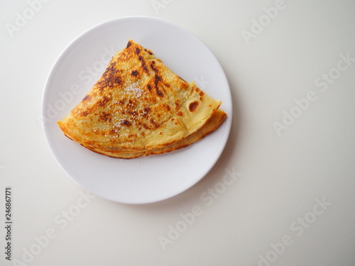 Traditional french crepe (or pancake) on a white plate, with sugar on top (called crêpe Suzette), white background