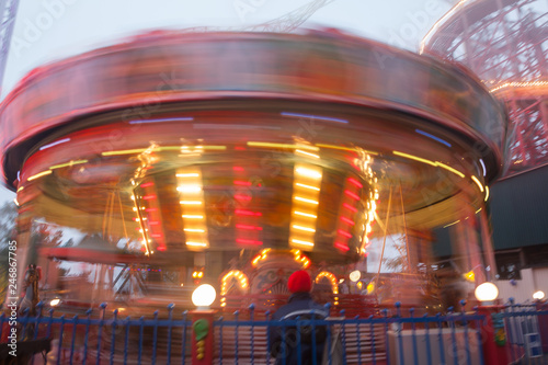 A blurry colorful carousel in motion at the amusement park  evening illumination. The effect of bokeh and long exposure.