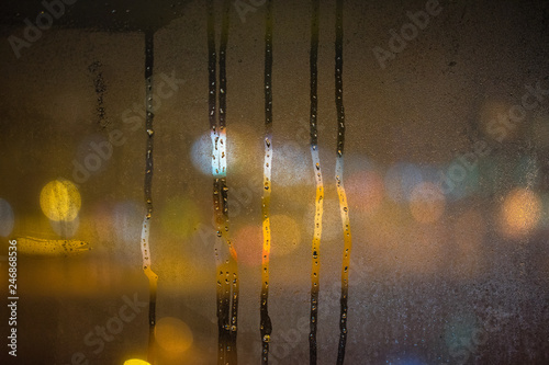 smudges on the frozen glass, misted glass, night lights bokeh on background