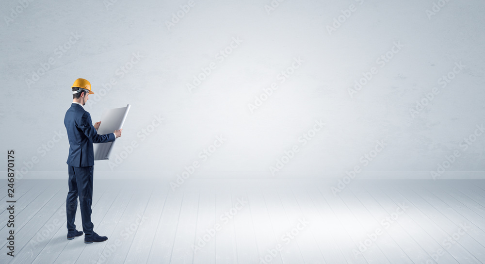 Young architect with construction helmet standing in an empty space and holding a plan
Young architect with construction helmet standing in an empty space and holding a plan