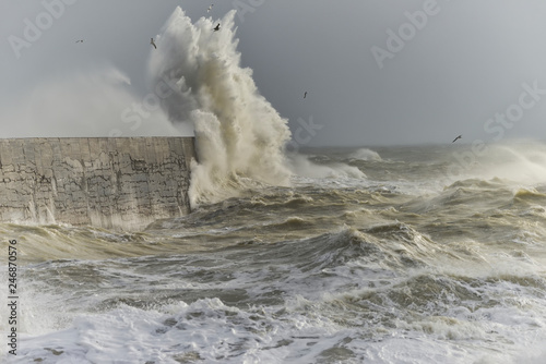 Stunning dangerous high waves crashing over harbor wall during windy Winter storm at Newhaven on English coast