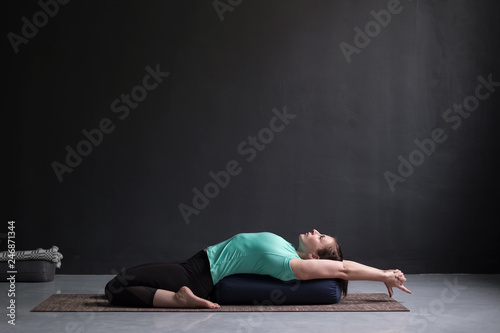 Billede på lærred Beautiful athletic girl doing yoga supta virasana asana using bolster