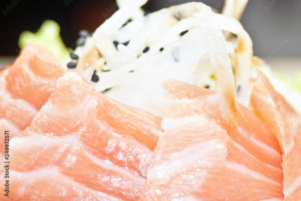 Raw salmon slice or salmon sashimi in Japanese style fresh serve on ice with fresh wasabi photo in indoor low lighting. Raw salmon slice or salmon sashimi in Japanese style fresh serve on ice with fresh wasabi photo in indoor low lighting.