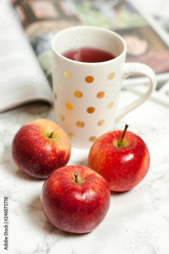 Czerwone jabłka i kubek na stole