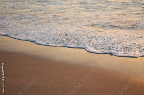 Beach floor during sunset with white foam and orange sand