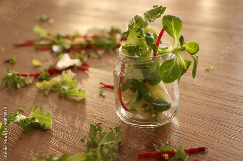 Green salat leaves and pieces of cutted beetroot in jar of glass