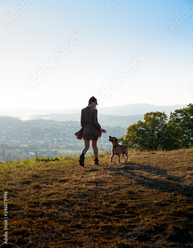Adorable young girl playing running with her cute dog on nature during sunset © alex_marina