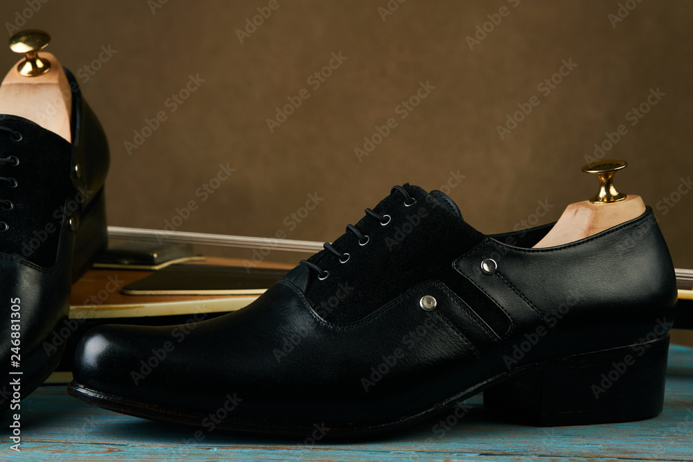 Leather mens shoes and bass guitar over brown background with copy space Leather mens shoes and bass guitar over brown background with copy space