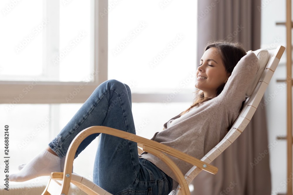 Relaxed calm young woman lounging sitting in comfortable wooden rocking  chair breathing fresh air dreaming, happy lazy girl chilling relaxing  enjoying no stress free peaceful quiet weekend at home Stock Photo