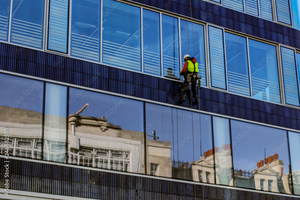 Man climb outside for cleaning window glass of high tower