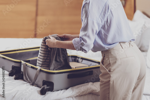 Close up of optimistic woman folding her suitcase