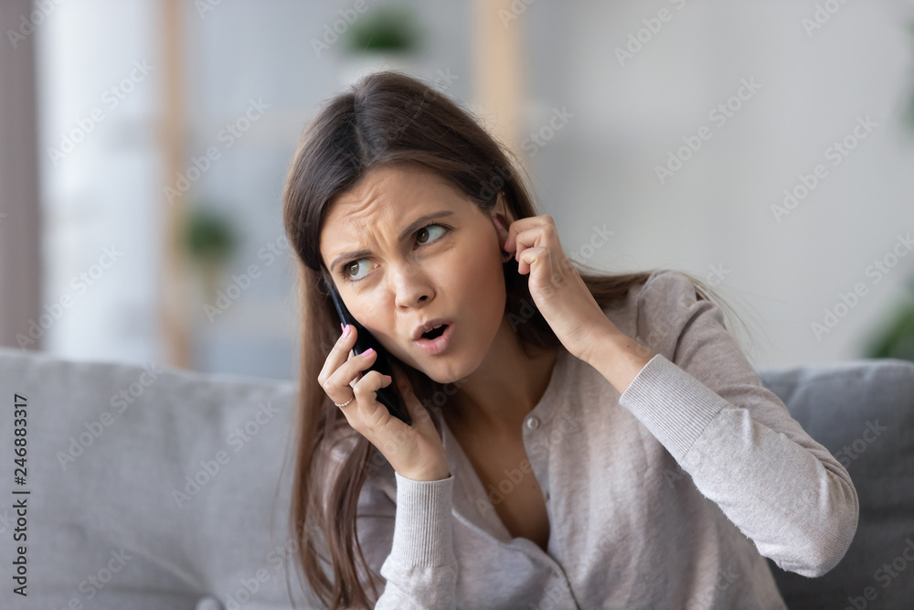 Annoyed young woman talking on the phone not hearing bad signal lost no mobile connection on cellphone, irritated girl closing ear frustrated by communication telecommunication service problem indoor Annoyed young woman talking on the phone not hearing bad signal lost no mobile connection on cellphone, irritated girl closing ear frustrated by communication telecommunication service problem indoor