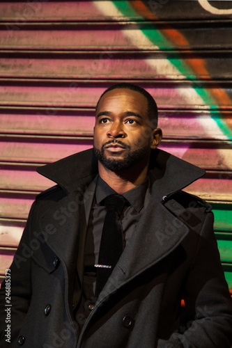 Thoughtful man in coat standing near shutter photo