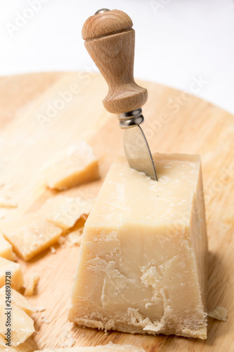 Sliced Parmesan with cheese knife inside on the wood surface