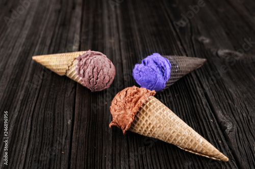 caramel, chocolate and blueberry ice cream in waffer on wooden background © Vaceslav Romanov