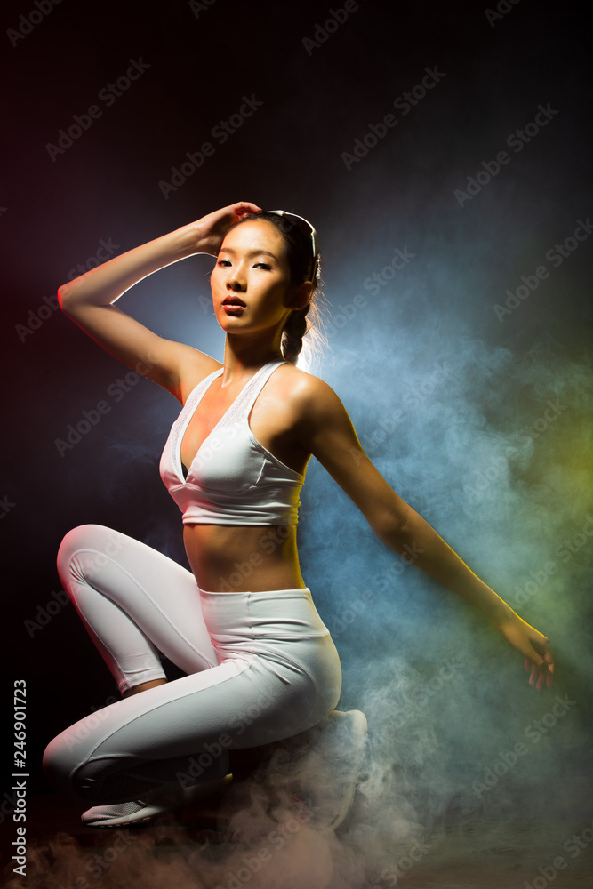 Obraz premium Asian Tan Skin Fitness women exercise wear white gear suit in Fog Smoke Dark background environment, studio lighting yellow back light copy space, concept ready start to run sunglasses