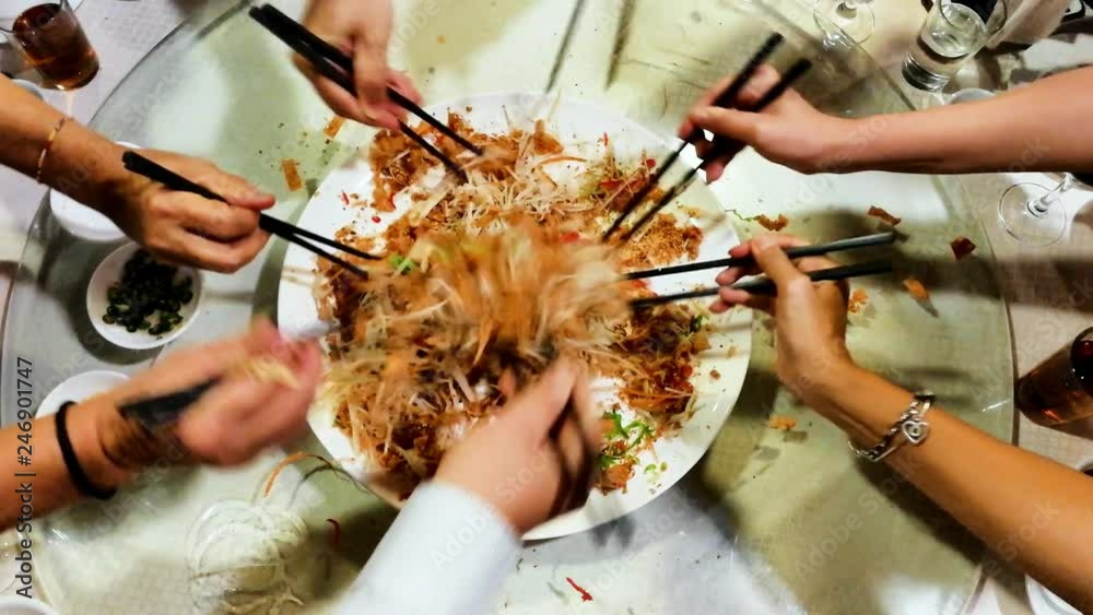 People tossing yee sang or yusheng during Chinese New Year dinner as symbol of good luck
