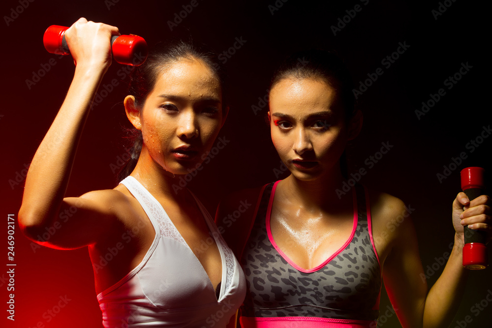 Two Asian Tan Skin Fitness women exercise boxing weight punch in Fog Smoke Dark background environment, studio lighting yellow back light copy space, concept 2 Woman Can Do Sport 6 packs Two Asian Tan Skin Fitness women exercise boxing weight punch in Fog Smoke Dark background environment, studio lighting yellow back light copy space, concept 2 Woman Can Do Sport 6 packs