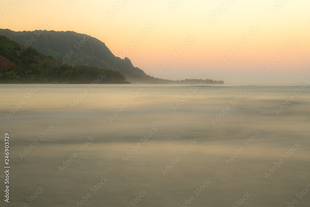 Sunrise lights the dawn sky above Hanalei Bay with the Na Pali coast in the background near Hanalei, Kauai, Hawaii