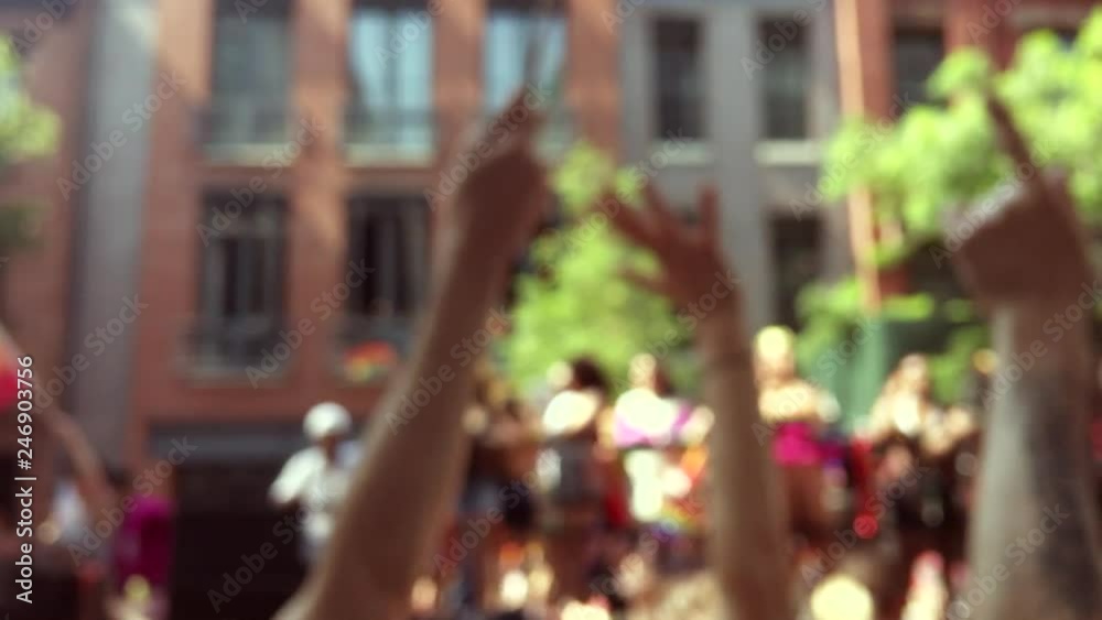 Rainbow flags flying on a float and in the hands of spectators on the sidelines in an abstract view of a summer gay pride parade in Greenwich Village New York City