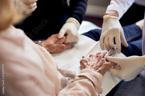 female doctor injecting the hand of an elderly woman photo