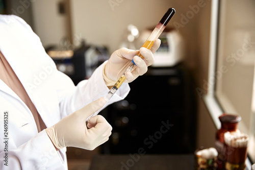 female doctor drawing prp from a vial with a syringe photo