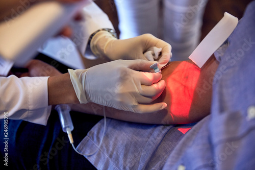 female phlebotomist using vein finder on caucasian man