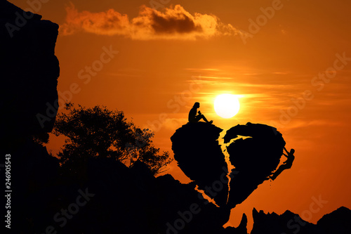Couple on the broken heart shape rock on the mountain with red sky sunset